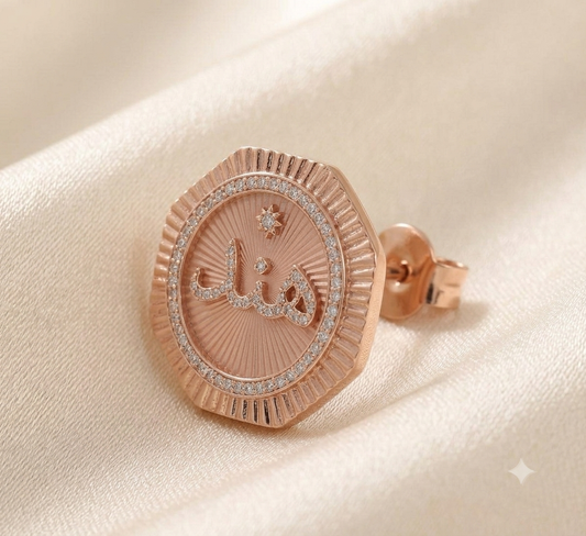 Fluted rose-gold name stud with octagonal fluted rim, pave crystal inner ring and engraved name panel on satin.