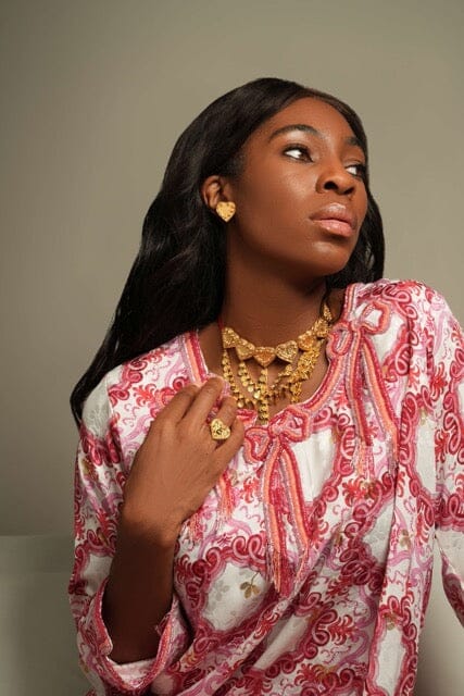 Sirr Eternal heart earring as gold-tone heart stud on model’s left ear, three-quarter portrait view