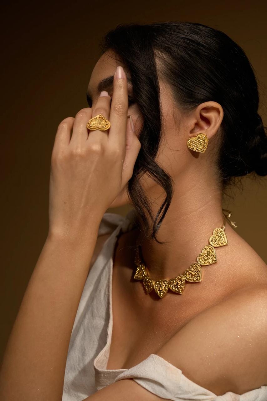 Sirr Eternal heart earring shown as a gold textured heart stud on model's ear